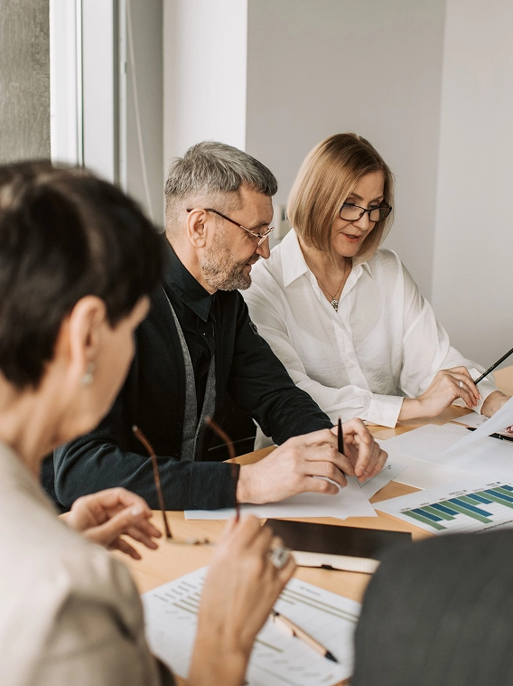 Group of colleagues reviewing printed charts and documents at a conference table