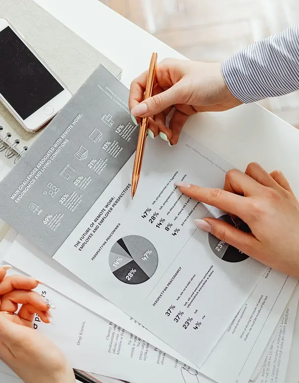 Two people reviewing a printed report with pie charts and percentage data at a desk